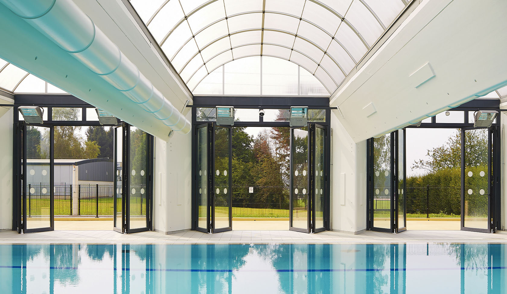 Curtain walled pool building with a vaulted glazed roof
