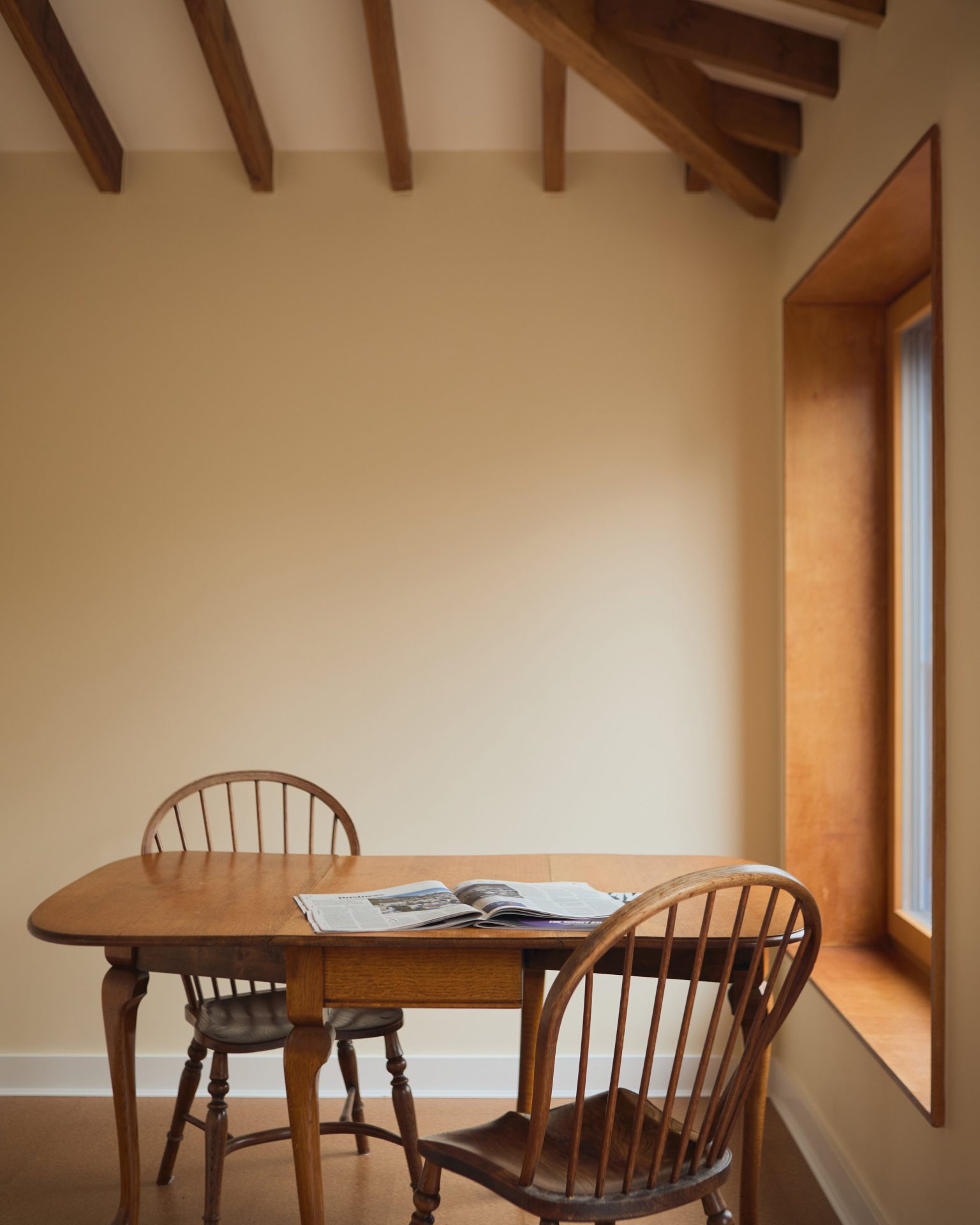 Dining area beside a deep timber window reveal