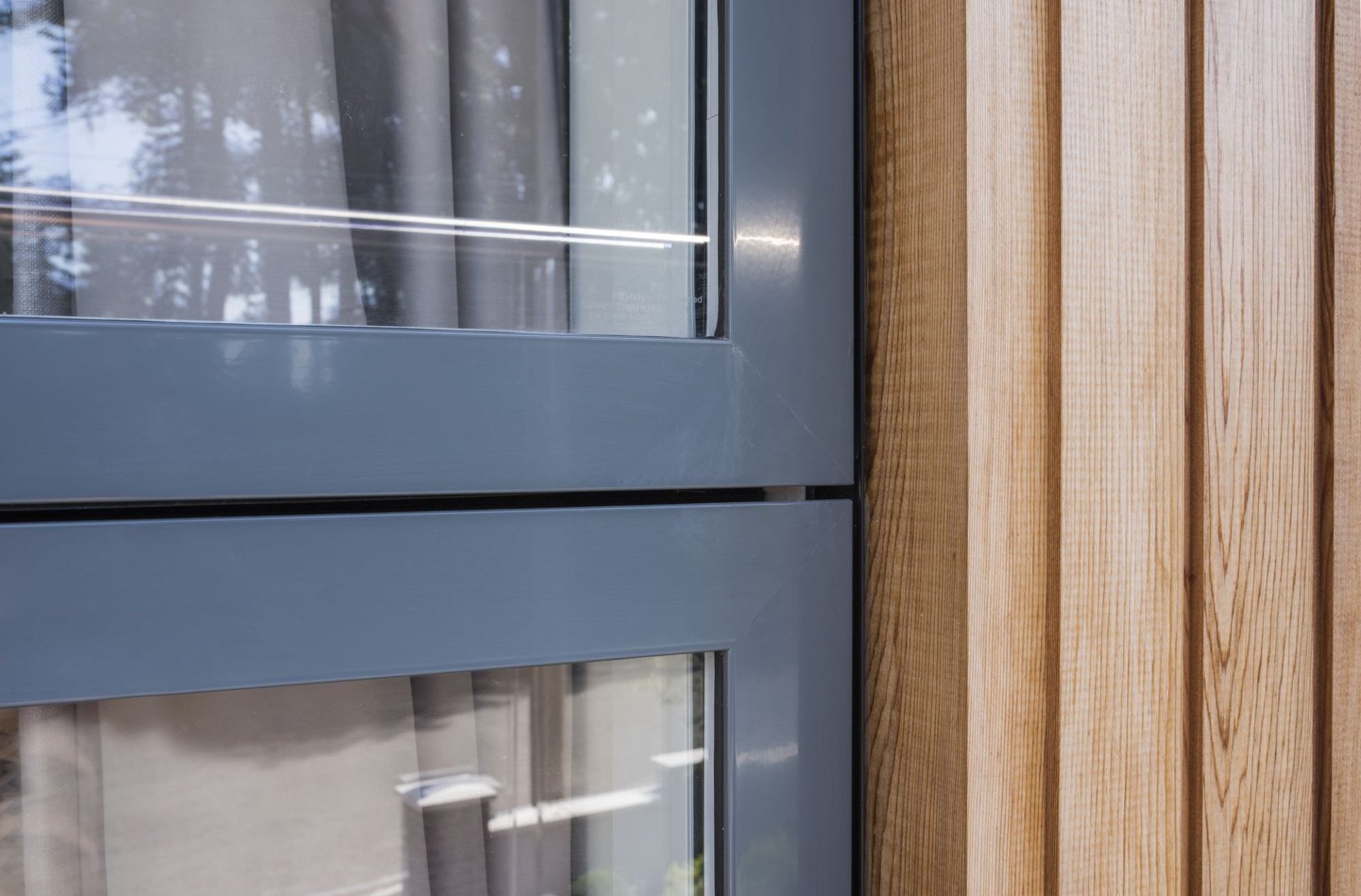 Close view of a grey VELFAC 200 frame beside timber cladding
