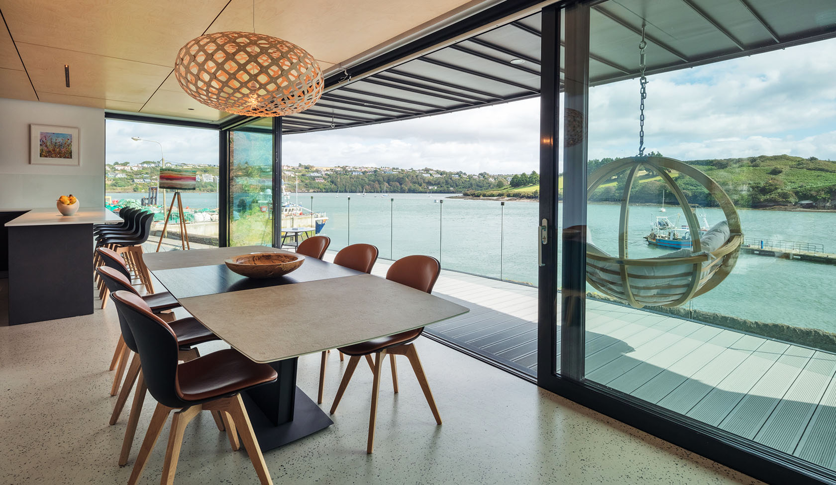 Dining space with aluminium sliding doors framing an estuary view